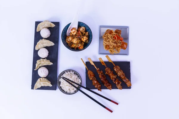 Grytlappar, sojasås, vitt ris, tofuost, ätpinnar nudlar. vit bakgrund — Stockfoto
