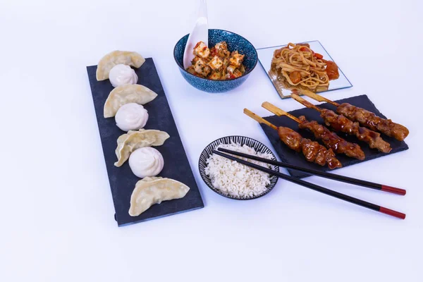 Grytlappar, sojasås, vitt ris, tofuost, ätpinnar nudlar. vit bakgrund — Stockfoto