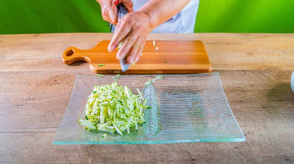 Chef che prepara zucchine julienne. strisce di zucchine su un piatto di vetro — Foto Stock