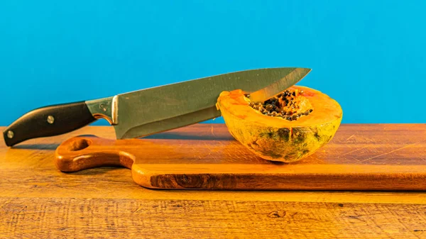 De helft van de rijpe papaja, mes, geïsoleerd. Houtsnij plank, close-up — Stockfoto