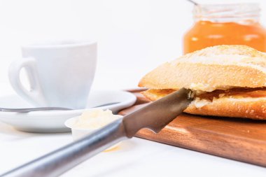 Ahşap bir kesme masasında taze el yapımı kırsal ekmek ile sabah kahvaltı masası. Beyaz arka planda yalıtılmış.