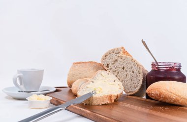 rustik ahşap masada ev yapımı reçel çekim ile tereyağı ve kavanoz ile tahıl ekmek dilimleri. Beyaz arka plan.