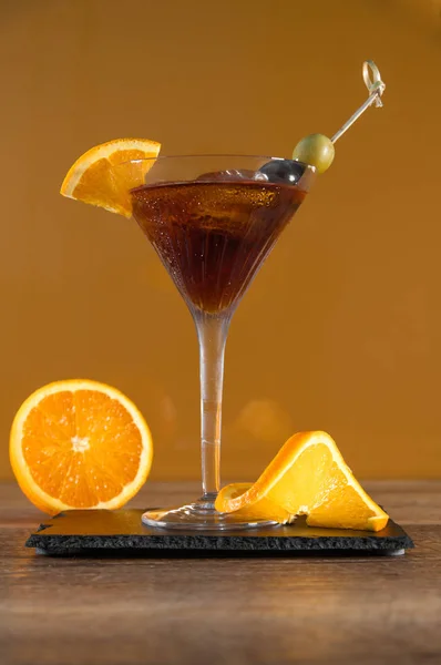 Klasyczny koktajl alkoholowy z czerwonym wermut, lód i koktajl oliwkowy w Martini szkła, żółte tło — Zdjęcie stockowe