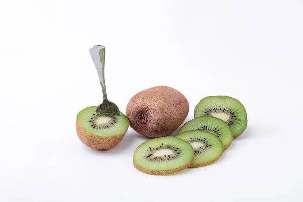 Un kiwi entero, uno cortado por la mitad con una cuchara y rodajas de kiwi verde con semillas - Delicioso bocadillo de kiwi fresco —  Fotos de Stock