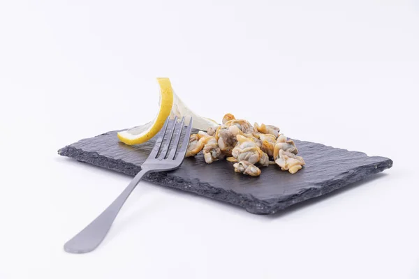 Verse kokkels geserveerd op een zwarte stenen tafel vergezeld van citroen — Stockfoto