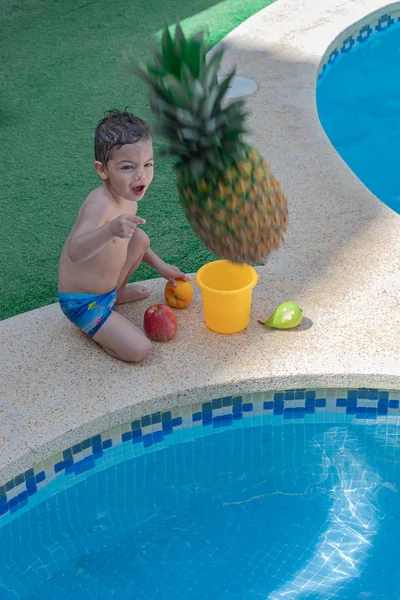 Petit enfant jetant un ananas à la piscine . — Photo