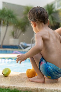 Yüzme havuzuyanında oynayan küçük bir Sırt çömelmiş küçük çocuk yakın
