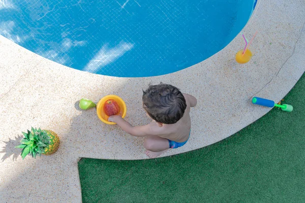 Vue aérienne d'un enfant jouant à côté de la piscine avec des fruits — Photo