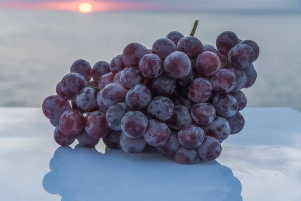 Tasty and sweet bunch of freshly harvested purple grapes on a white table — Stock Photo, Image