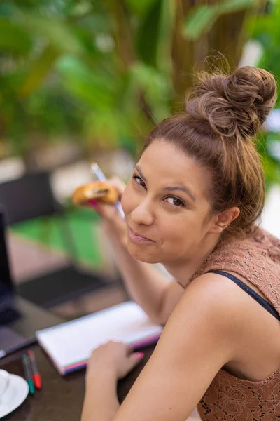 Una hermosa estudiante sonriendo a la cámara mientras hace su tarea —  Fotos de Stock