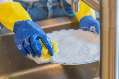 Bulaşık gereçleri mutfak temizliği - Bulaşık yıkama işlemi - Köpük bir sürü mavi ve sarı plastik eldiven