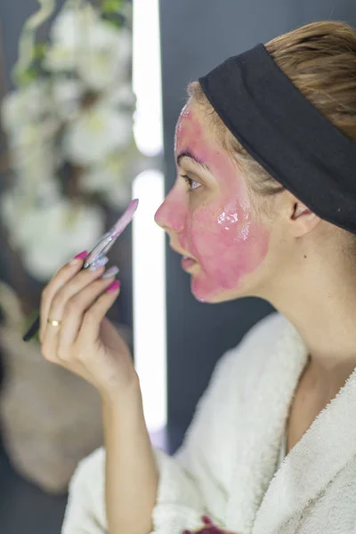 Vue latérale d'une fille blanche qui applique un masque rose sur son visage - Organic Beauty Cosmetics — Photo