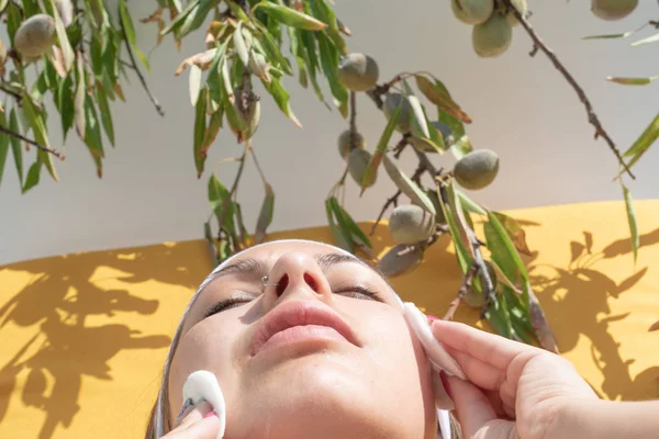Расслабленная женщина наносит макияж на лицо - декоративные зеленые фрукты на заднем плане — стоковое фото