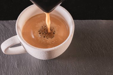 Beyaz bir fincan üzerine kahve döken bir makinenin yakın çekim