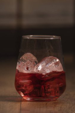 Lezzetli kırmızı yaz kokteyli ahşap bir masada buz küpleri ile servis