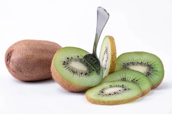 Gustoso snack tropicale - Un intero kiwi, uno tagliato a metà con un cucchiaio e fette di kiwi verde con semi - Con uno sfondo bianco — Foto Stock