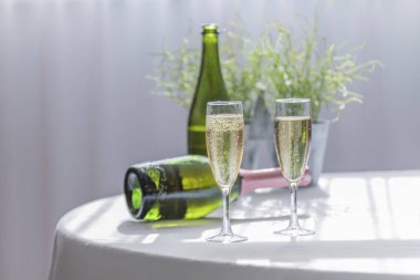 Lüks ve kabarcıklı şampanya arka planda iki şişe ile iki zarif tatil bardakları servis. Kutlama kavramı.