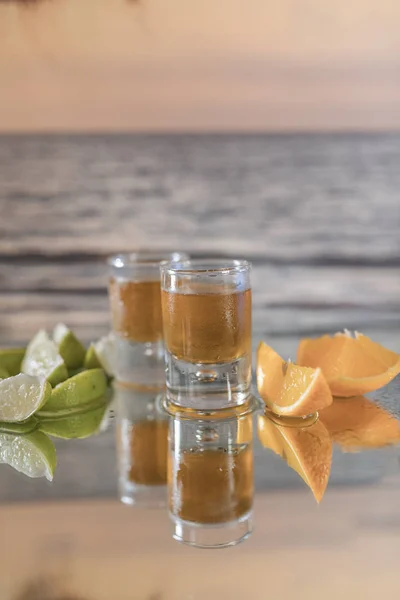 Rhum servi en deux verres avec des tranches d'orange et de citron sur une table en verre dans la mer . — Photo