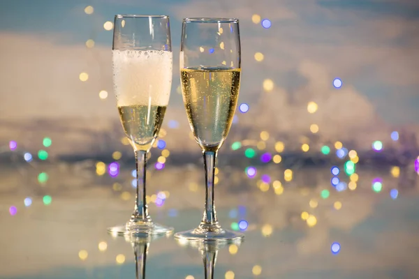 Champanhe espumante e cava amarela servidos em dois copos de vidro com o fundo iluminado por muitas pequenas luzes de Natal. Conceito de festa e celebração . — Fotografia de Stock