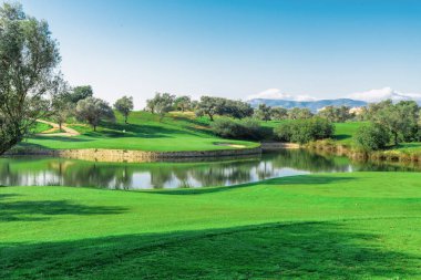 Bir göl ve s etrafında ağaçların çok büyük yeşil golf sahası
