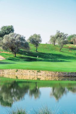 Arka planda bir golf sahası ve birçok t ile güzel bir göl