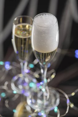 Lüks ve köpüklü şampanya havadan görünümü şampanya ile başka bir bardak yanında bir bardak ve arka planda birçok odaklanmamış yapay ışıklar servis. Kutlama kavramı.