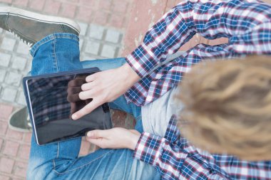 Bir tablet üzerinde sosyal ağlar kontrol sarışın bir adam üst görünümü. Teknolojik gençlik kavramı.