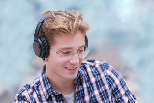 Close-up van een lachende blonde jongen met een bril en een koptelefoon. — Stockfoto