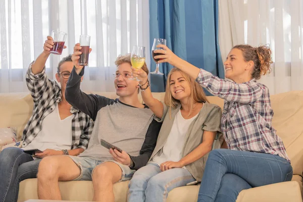 Lächelnde Frauen heben ihre Getränke mit einem blonden Jungen in Form einer Feier in die Höhe, alle sitzen eines Nachmittags auf einem Sofa. Konzept der Geselligkeit. — Stockfoto