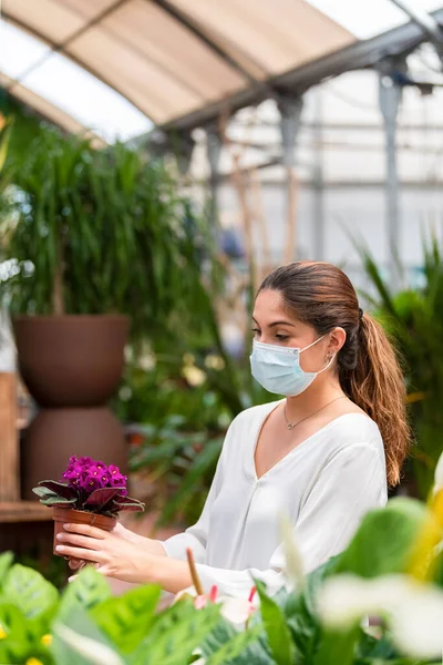 Mujer Joven Usando Una Máscara Quirúrgica Revisando Una Hermosa Planta — Foto de Stock