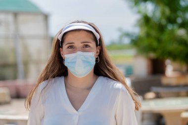 Spor vizör ve cerrahi maske takan genç bir kadının odak noktası dışında çekilmiş bir fotoğrafını çek. Yeni yaşam tarzı ve güvenlik kavramı.