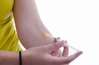 Sol kolundaki şırıngayla arka planda kalan genç bir kadının fotoğrafını çek. Sağlık ve Tıp Konsepti.