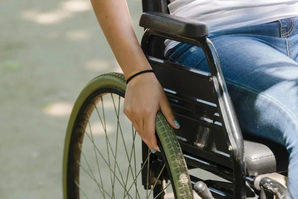 女性の手がフォーカス外の背景にそれに休んで車椅子の車輪の上を閉じます 障害と医療の概念 — ストック写真