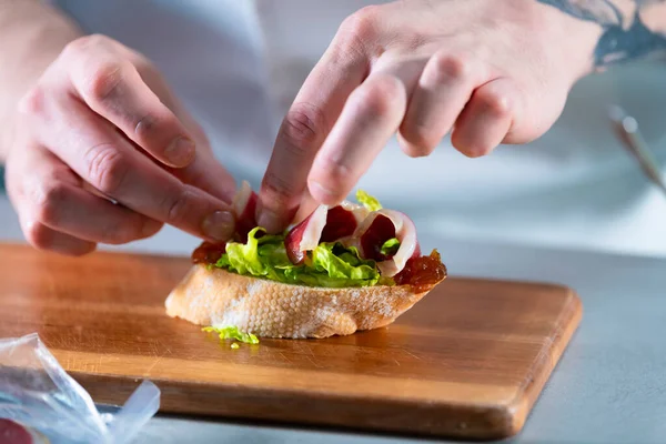 Мужские руки готовят открытый сэндвич с салатом, карамельным луком и ветчиной. Концепция здорового питания. — стоковое фото