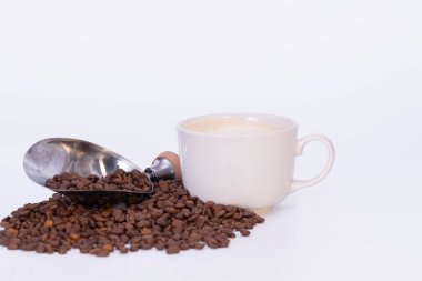 Kahve çekirdeği ve beyaz arka planda kahvaltı fincanı