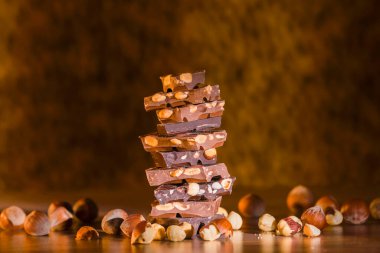 Fındıklı ve bademli çeşitli çikolata parçalarının yakın plan çekimi odak arka planında fındıkla çevrili bir kule oluşturuyor.