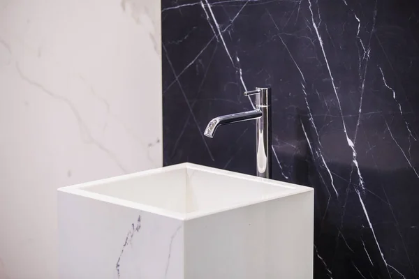 Marble sink on the background of a marble wall, black white bathroom completely in marble.