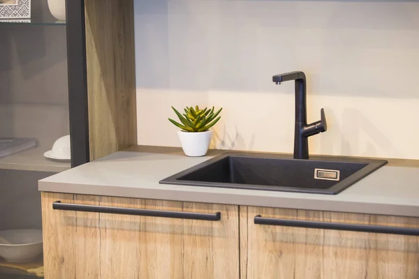 Water faucet in the modern kitchen. Black faucet and wooden kitchen.