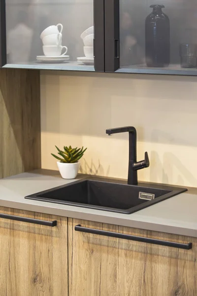 Water faucet in the modern kitchen. Black faucet and wooden kitchen.