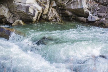 Kayalar ile açık nehir dağlara doğru küçük şelale yol açar..