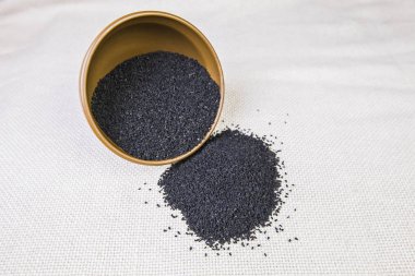 Bir plaka ışık çuval bezi arka plan üzerinde siyah kimyon. Seçici odak.