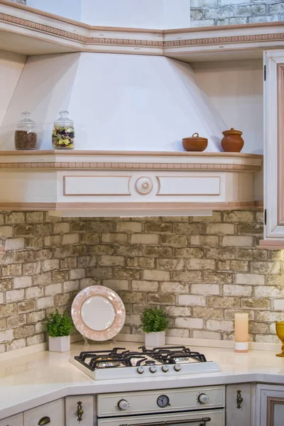 Cozy kitchen, hob. Brick apron in the kitchen. Part of the kitchen with hood.