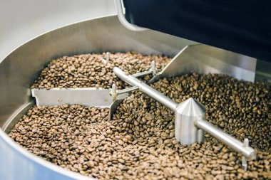 Taze kavrulmuş aromatik kahve çekirdekleri bir modern kahve kavurma makinesi.