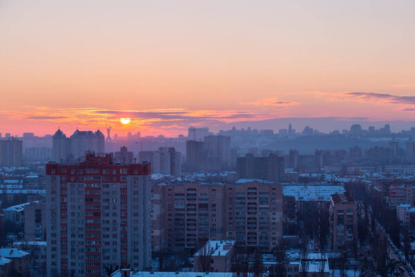 Sunset in Kiev, evening view of the panorama Kiev city. Red sun, fog and smog in the capital of Ukraine.