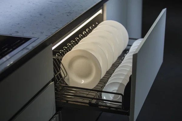 Modern kitchen, storage space for plates, illuminated drawer in luxury kitchen