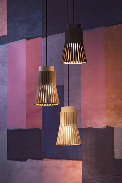 Suspended wooden lamps. Modern chandeliers of wood in Scandinavian style on a colorful background