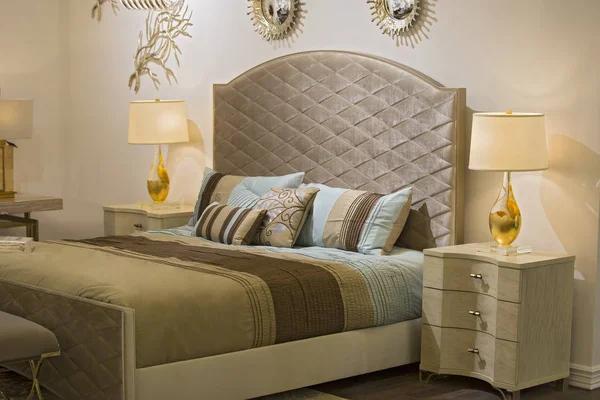 Модная современная спальня, кровать, люстра, зеркала на стене, тумбочка и лампа, красивые текстиль на кровати. Шикарный дизайн спальни — стоковое фото