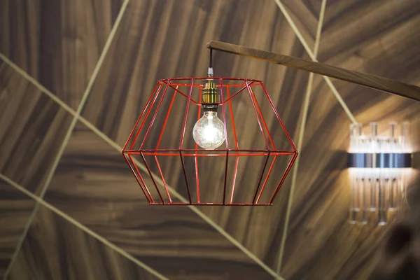 Blízká moderní červená barevná měděná lampa se žárovkou na dřevěném pozadí — Stock fotografie