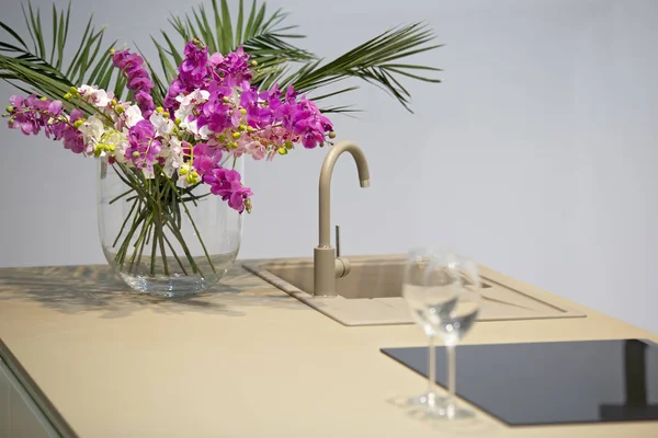 Diseño de cocina minimalista con isla y grifo. Cocina gris-blanca y copas de vino sobre la mesa — Foto de Stock