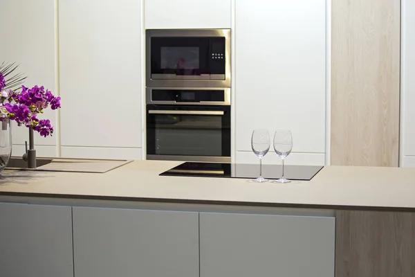 Desain dapur yang minimalis dengan pulau. Abu-abu-putih dapur dan gelas anggur di atas meja — Stok Foto